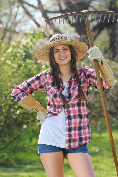 Beautiful smiling gardener with a rake — Stock Photo, Image