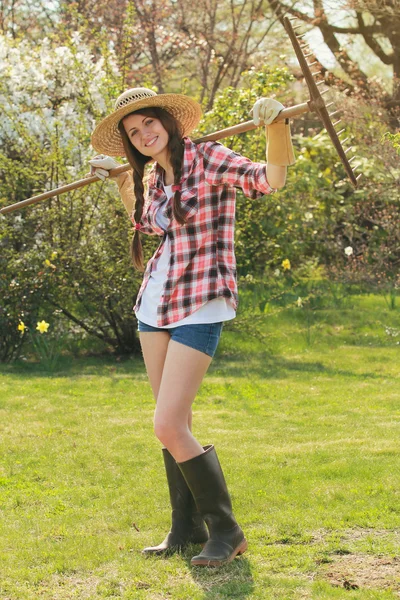 Happy smiling girl posing with a rake — Stock Photo, Image