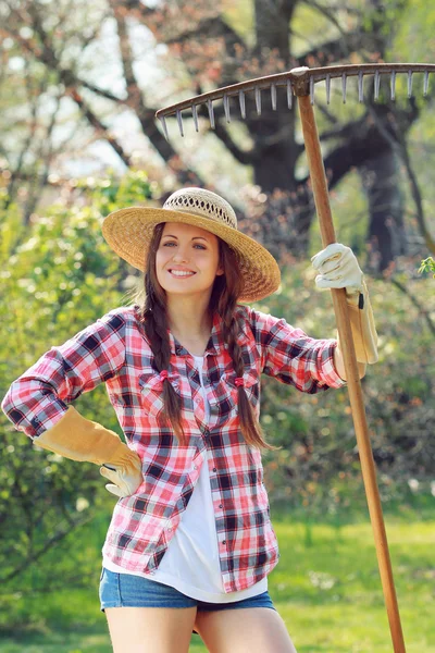 Femme souriante pose avec un râteau — Photo