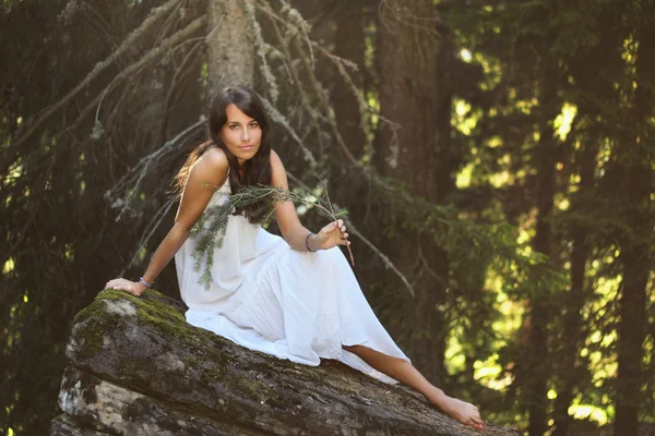 Beautiful young woman on forest rock — Stock Photo, Image