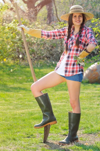 Belle fille souriante pose avec une pelle dans un jardin — Photo