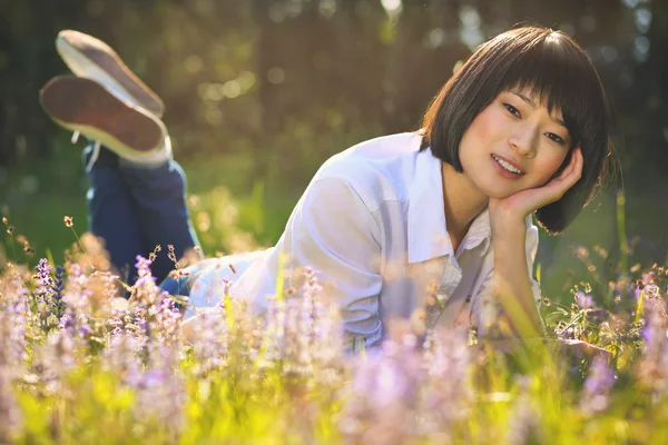 Menina asiática bonita relaxante entre flores — Fotografia de Stock