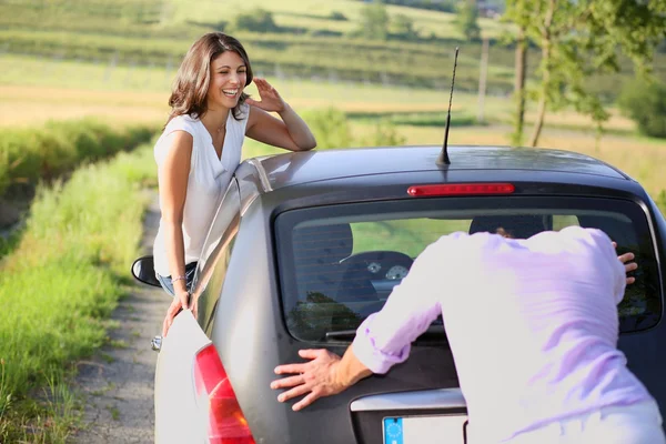 Смеющаяся девушка и парень толкают машину — стоковое фото