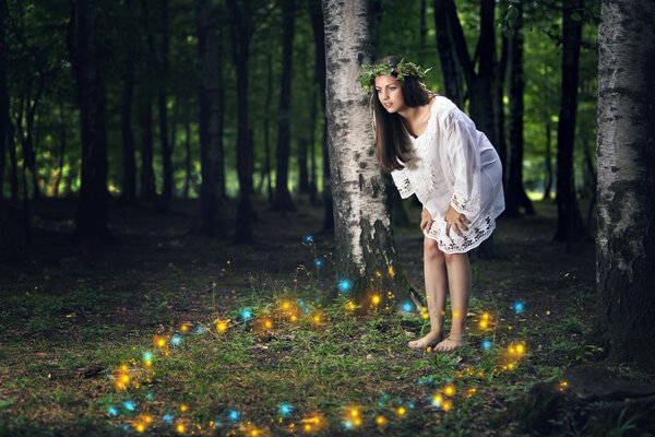Beautiful girl staring at the dance of the forest spirits . Fantasy and fairy tale