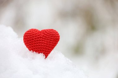 Kış ormanlarında kardaki aşk kalbi. Sevgililer günü kartı, aşkın kırmızı örgü sembolü, romantik olaylar için arka plan, Noel kutlaması.