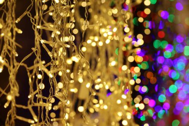 Elektrikli çelenklerdeki Noel ışıkları. Renkli yeni yıl süslemeleri, şehirde şenlikli aydınlatma