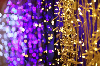 Elektrikli çelenklerdeki Noel ışıkları, seçici odaklanma. Renkli yeni yıl süslemeleri, şehirde şenlikli aydınlatma