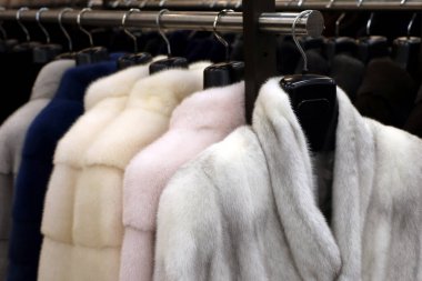 Mağazadaki askıda üst üste kürk mantolar. Kadın modası, farklı renklerde kürk kürk.