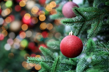 Bulanık ışıklı arka planda Noel oyuncağı topları. Kırmızı toplu yeni yıl ağacı, şenlikli süslemeler.