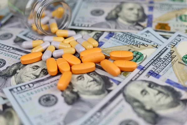 Kapsüllerdeki haplar bir şişeden Amerikan dolarlarına saçılmış. ABD 'de sağlık hizmeti kavramı, ilaç ticareti, uyuşturucu fiyatları, eczane, tıp ve ekonomi