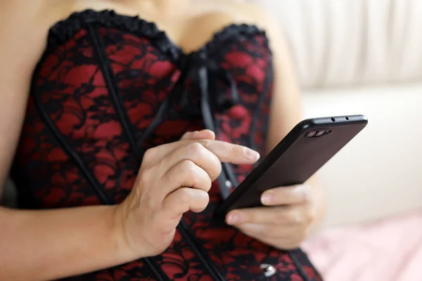 Gorąca Kobieta Czerwonym Gorsecie Siedzi Smartfonem Łóżku Pojęcie Komunikacji Online — Zdjęcie stockowe