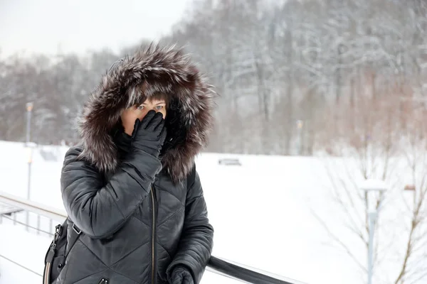 Jégeső Télen Bőrkabátban Prémkapucnis Áll Parkban Hóban Eltakarja Arcát Kesztyűvel — Stock Fotó