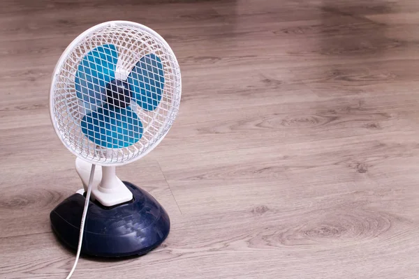 Small fan on the wooden floor closeup — Stock Photo, Image