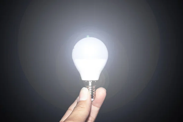 Glowing light bulb in hand in the dark — Stock Photo, Image