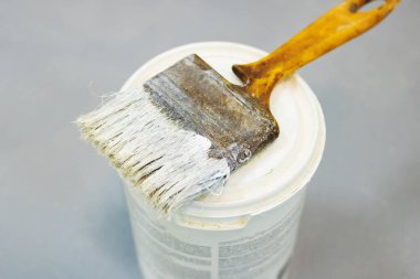 Boya fırçası ve boya kutusu gri bir zeminde, üst manzara