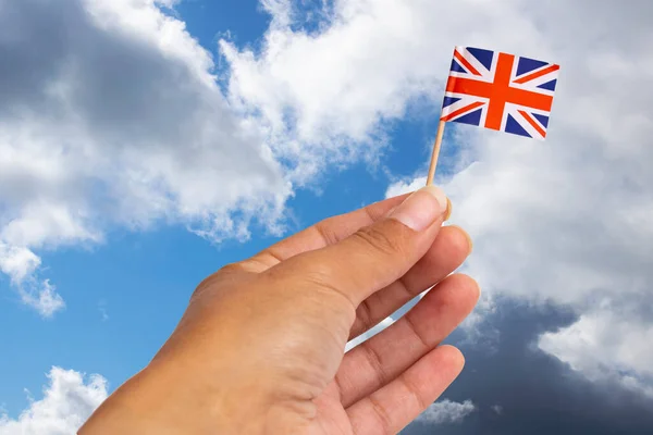 Small Britain flag in hand against the sky close up