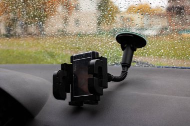 Arabanın ön camında telefonu var. Yakın plan.