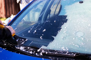 El, arabanın ön camını buzdan temizler.
