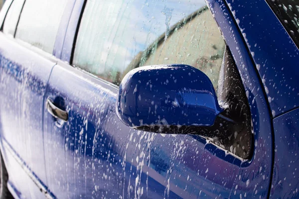 Μπλε αυτοκίνητο σε αφρό σε πλυντήριο αυτοκινήτων — Φωτογραφία Αρχείου