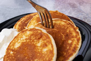 Krepler ve ekşi krema bir tabakta, ahşap bir masada. Yakın çekim.