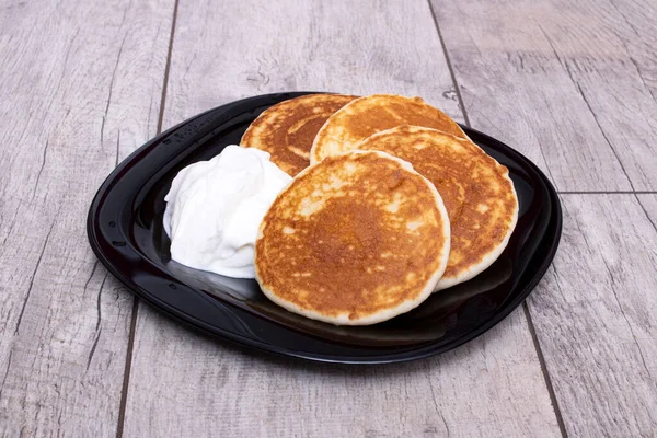 Pfannkuchen Und Saure Sahne Auf Einem Teller Auf Einem Holztisch — Stockfoto