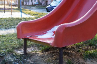 Yüksek bir evin avlusunda eski püskü bir çocuk kaydırağı.