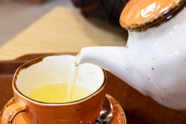 Çaydanlıktan fincana çay dökülüyor. Yakın çekim.