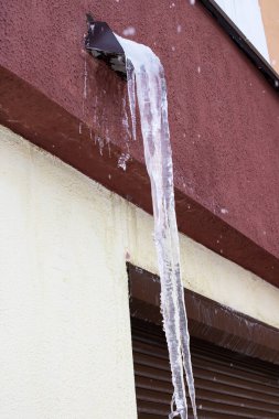 Evin çatısında büyük bir buz sarkıtı asılı.