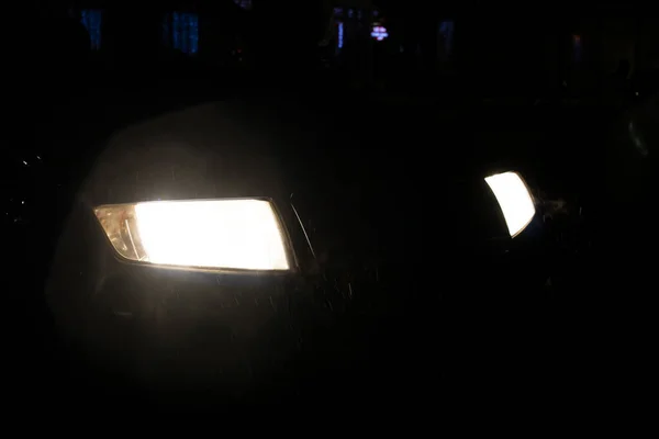 雨の中で暗闇の中で車のヘッドライトを閉じる — ストック写真