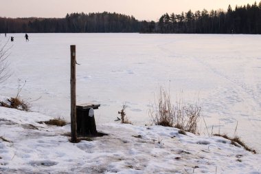Karlı bir gölün kıyısındaki sandalye