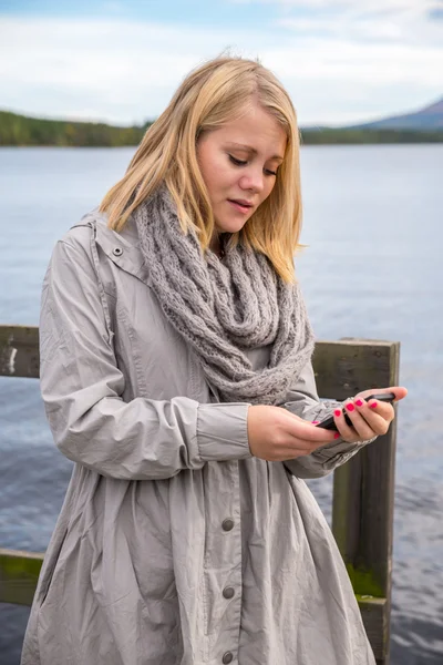 Ung kvinna läser på sin smartphone — Stockfoto