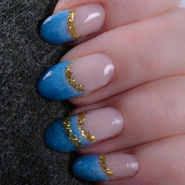 Δάχτυλα με μπλε γαλλικό μανικιούρ και glitter χρυσό Εικόνα Αρχείου