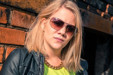 Kendine güvenen Bayan sarışın ayakta karşı bir tuğla