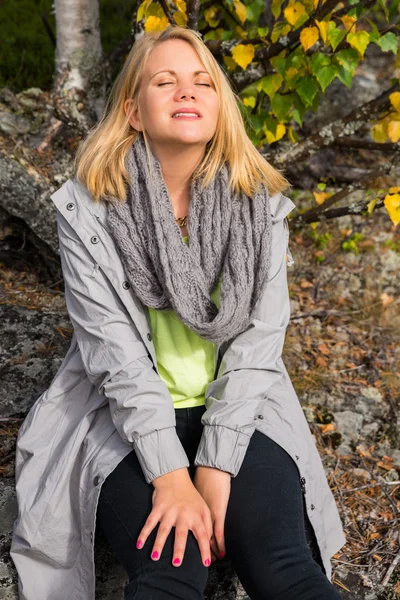 Woman enjoying life sitting on a rock — Stock Photo, Image