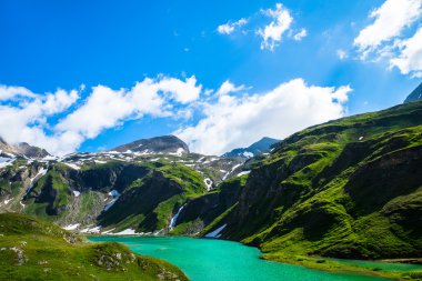 Turkuaz Gölü çevresinde yeşil tepelerin ve karlı dağlar ile ben