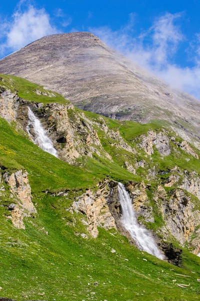 Green slopes with two waterfalls and a mountain peak — Stock Photo, Image