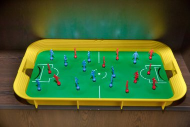 Kırmızı ve mavi oyuncuları olan top manzaralı masa futbolu. Langırt masası. Langırt masasının en üst görüntüsü. Oyuncuları ve topları olan mini masa futbolu..