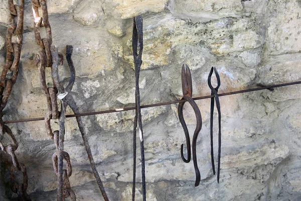 Η έκθεση της χειροτεχνίας σιδερά έργα παραδείγματα στον τοίχο στο τοπικό Εθνολογικό Μουσείο. Παλιά σκουριασμένα εργαλεία σιδερά στην πέτρα . — Φωτογραφία Αρχείου