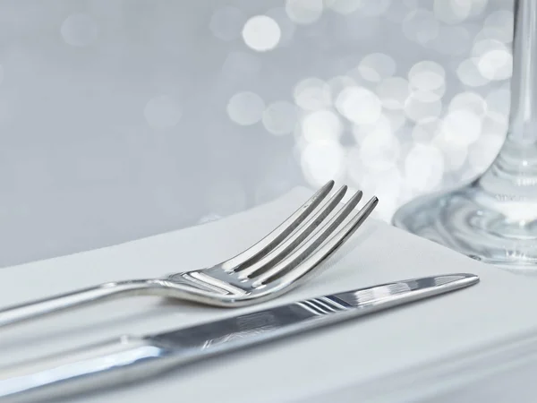 Tenedor y cuchillo en elegante mesa con fondo festivo Imagen De Stock