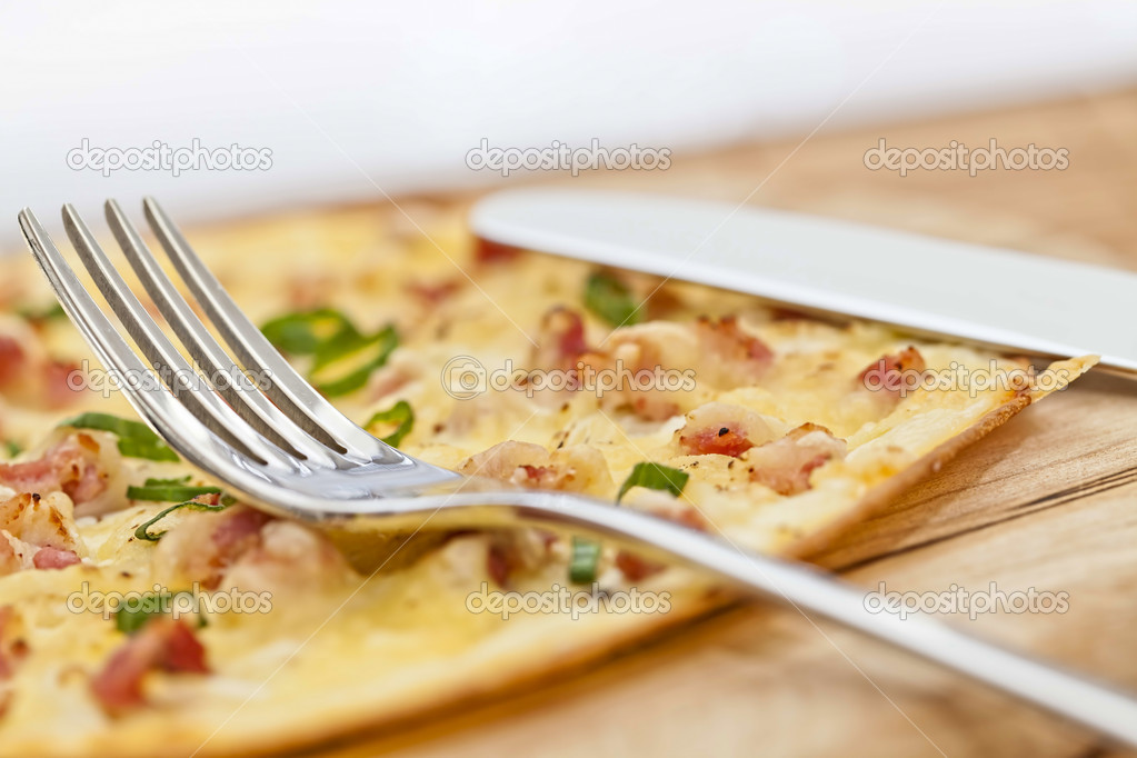 Tarte flambee with fork on wooden