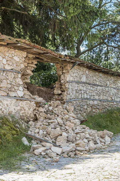 Parcialmente destruido parte de la valla de piedra de una casa en un pueblo búlgaro. Agujero en la pared. — Foto de Stock
