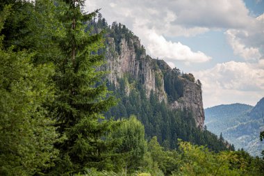 Parlak mavi gökyüzü ve kalın kabarık bulutlar, günbatımı manzarasında dar patikalı yeşil dağ sırtlarının üzerinde süzülüyor..