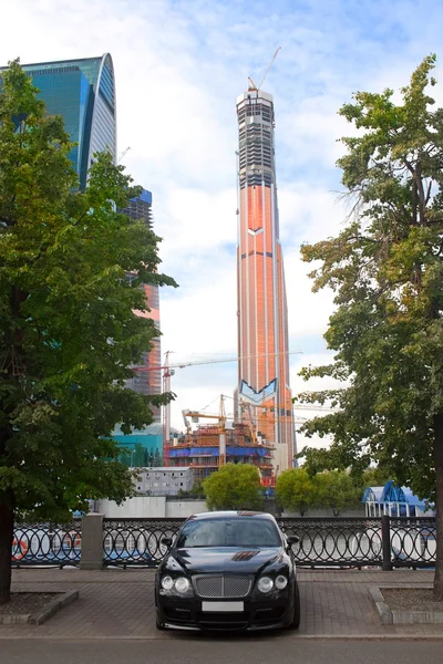 Car against the business center under construction — Stock Photo, Image