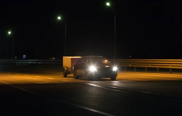 Samochód Przyczepą Porusza Się Wzdłuż Nocnej Podmiejskiej Autostrady — Zdjęcie stockowe