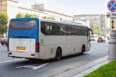 Beyaz şehir otobüsü cadde boyunca gidiyor.