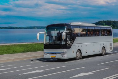 Turist otobüsü yazın göl kıyısında yol boyunca hareket eder.