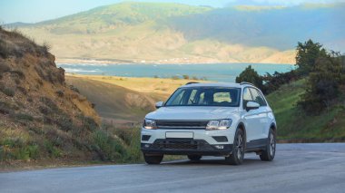 SUV bir yaz günü deniz kenarında dolambaçlı bir yol boyunca hareket eder.
