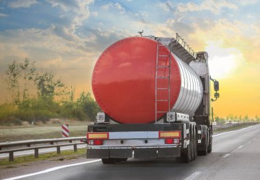 Yakıt kamyonu gün batımında güneşe doğru yol alıyor.