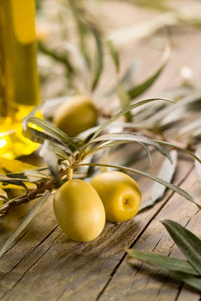 Zwarte olijven met fles van olie op een houten tabl — Stockfoto