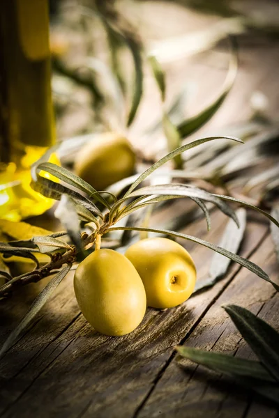 Organic olives with bottle of oil on a wooden table — Stock Photo, Image